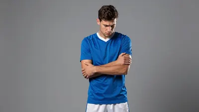A photorealistic image of a young, anonymous, waist-up, Rodez player in a blue jersey with white shorts, looking...