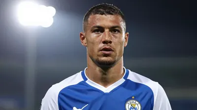 A 30-year-old Rodez player, with a muscular build, wearing a blue and white kit, looking determined, photographed with an...