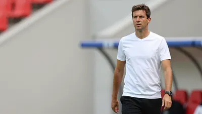 A 25-30 year old, male, French, football coach, wearing a white, short-sleeved, cotton shirt, and black, long pants, with...