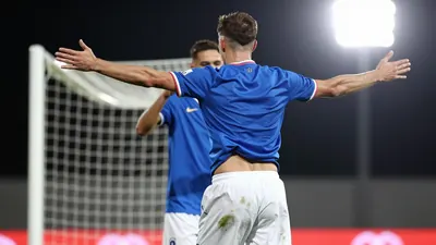 A tight action crop of an anonymous Rodez player celebrating a goal with a teammate, wearing a blue jersey and white shorts