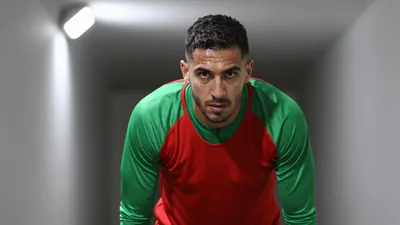 Mid-30s rugged midfielder, waist-up, intense gaze, sweat-glazed forehead, wearing a plain red and green training top...